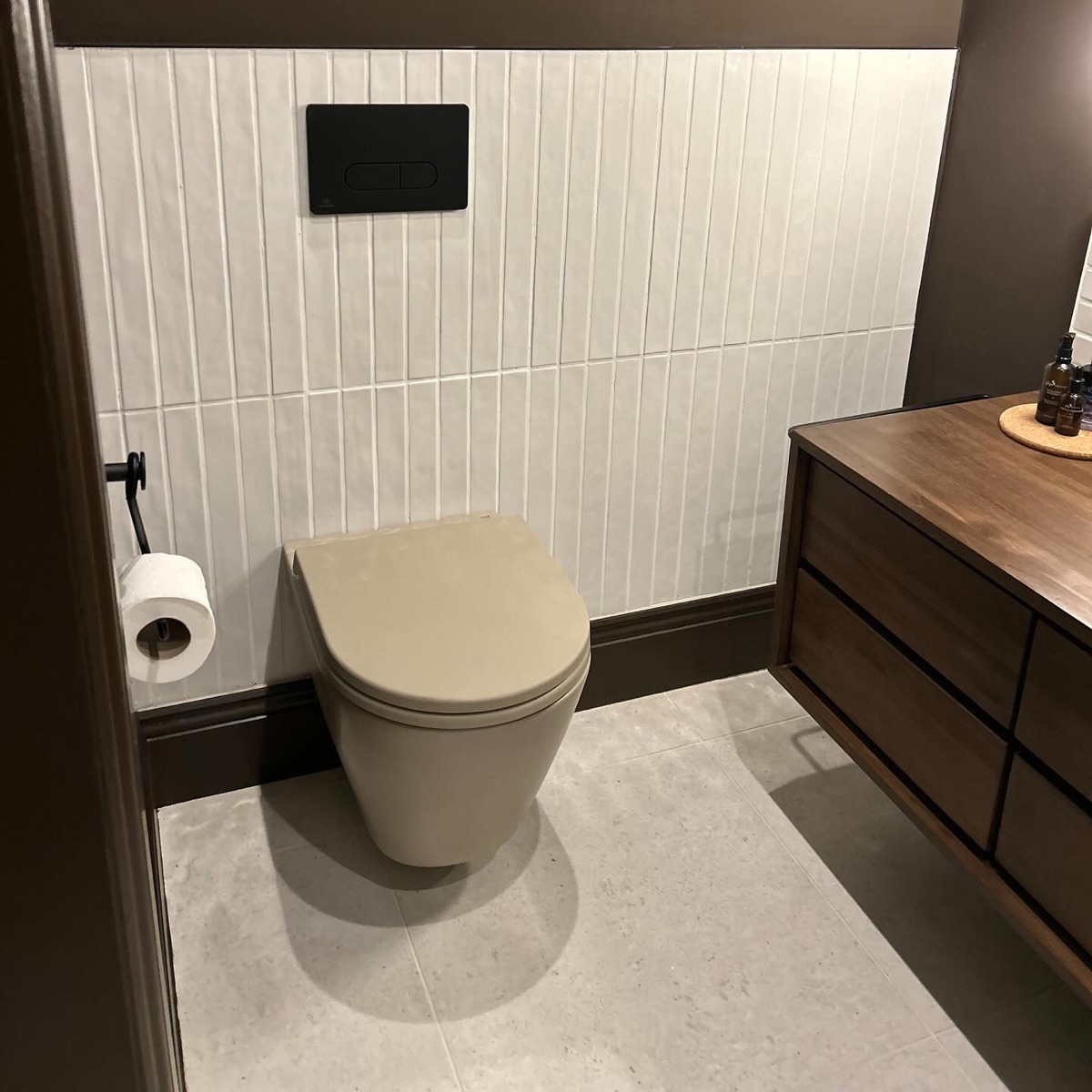 Wall-hung toilet with vertical tiles and walnut vanity